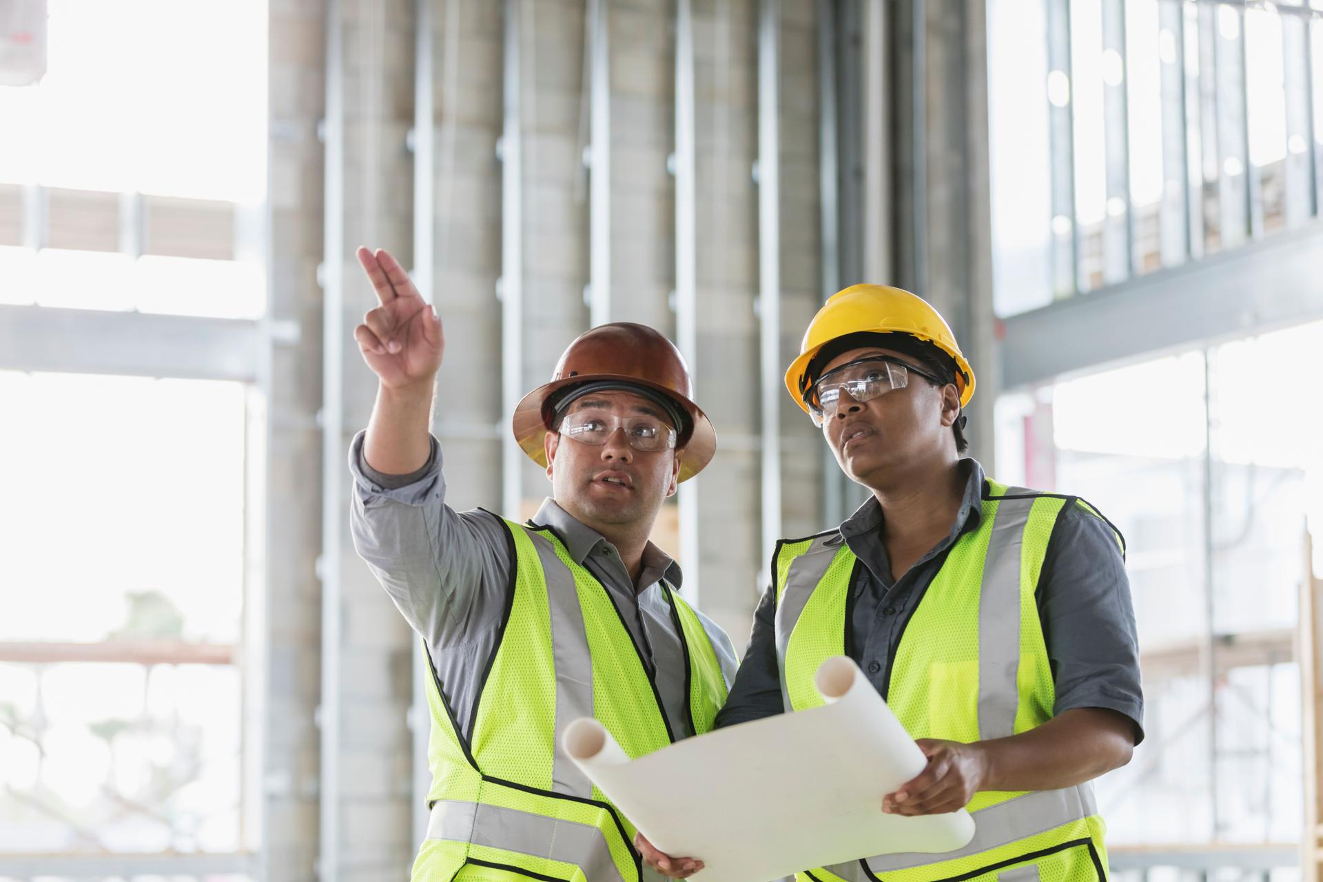 Construction workers discussing floor plans