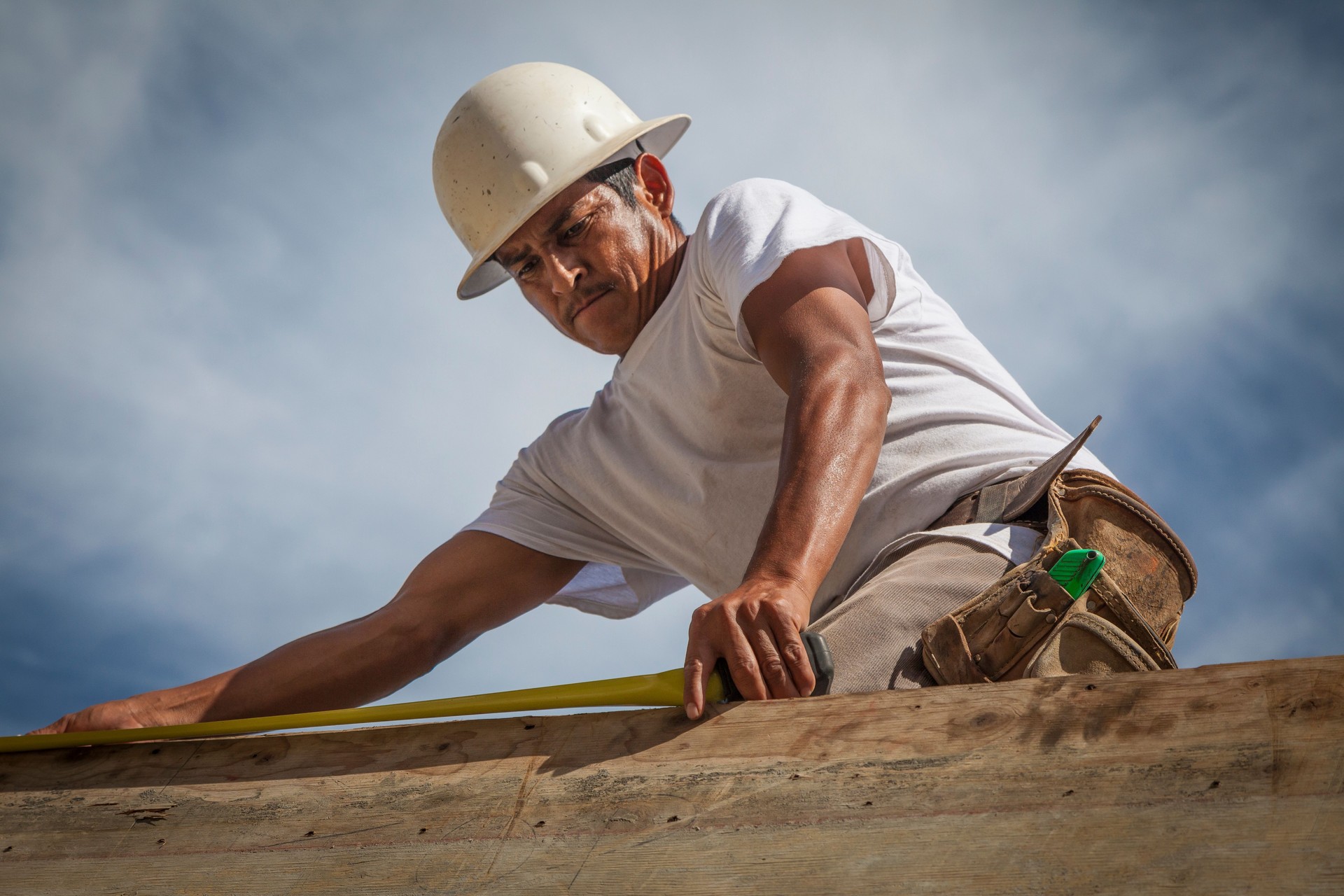 Construction Worker Measures Along Top of Wall